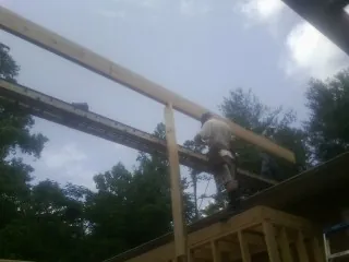 Carpenter setting a ridge beam over a new addition frame — Ice Dam Removal by Roofing Brothers in Sandy Spring