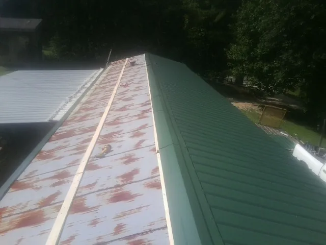Old rusted panels beside newly installed green metal roofing — Wind Damage Roof Repair by Roofing Brothers in Sandy Spring