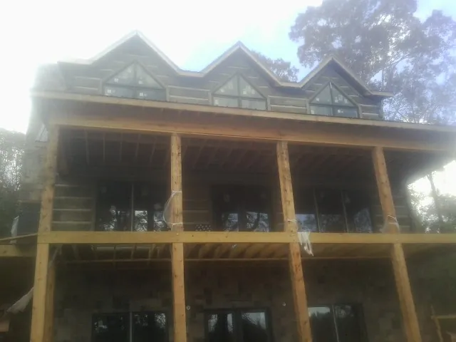 Dormers and porch framing on a large log home under construction — Roof Coating work by our crew in Sandy Spring