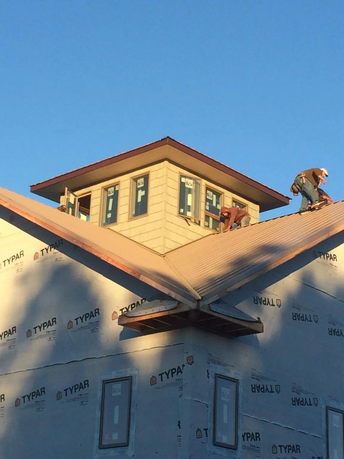 Roofers working around a rooftop cupola on a new metal roof at sunset — Roof Waterproofing in Sandy Spring by Roofing Brothers